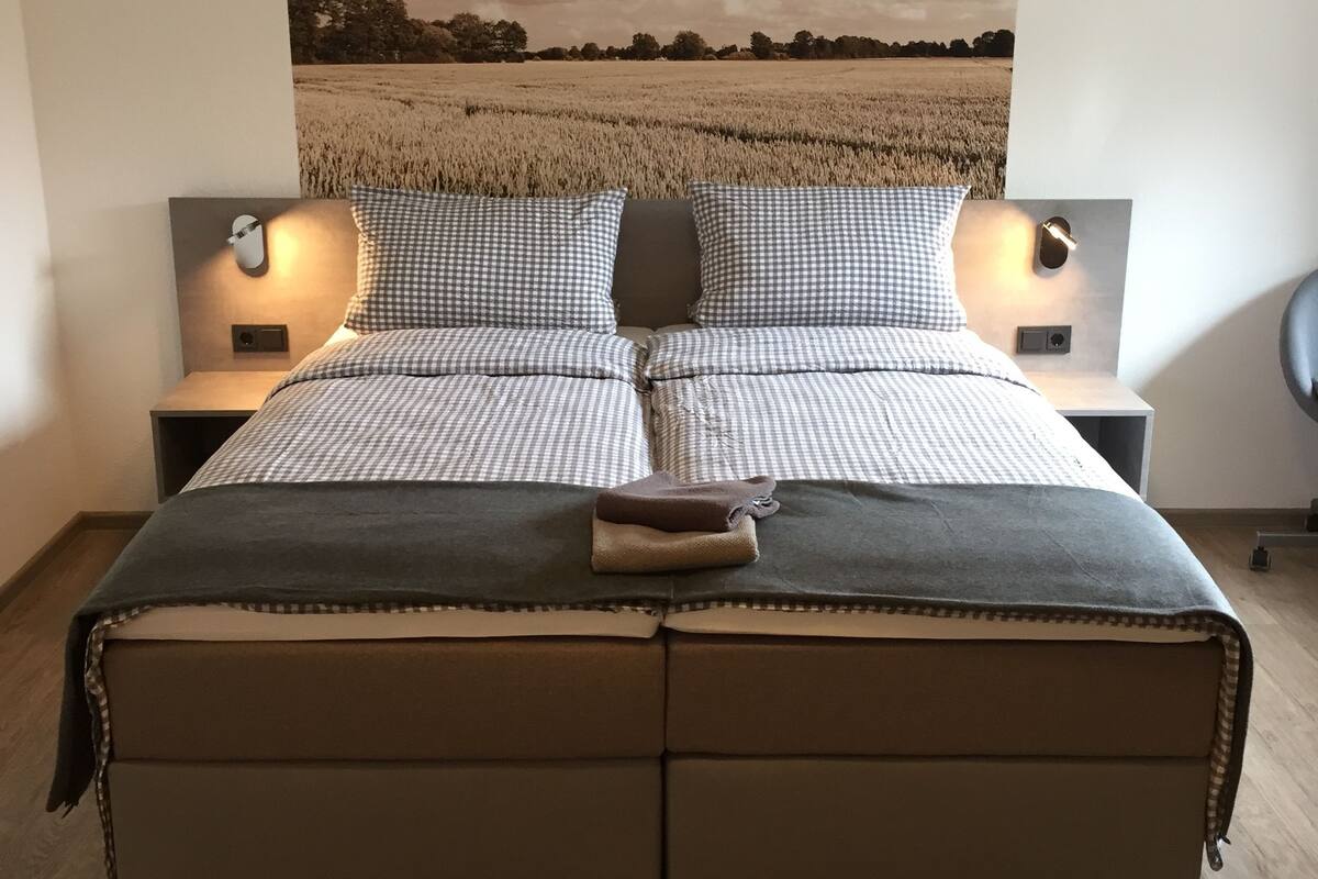 Een slaapkamer met een groot bed, twee nachtkastjes en een wandlamp.