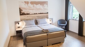 Een moderne slaapkamer met een groot bed, een nachtkastje, een stoel en een raam met gordijnen.