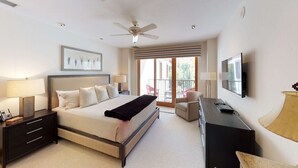 A bedroom with a bed, bedside tables, a desk, a chair, a TV, and a balcony with a view. - Vail Residences at Hotel Talisa (Vail)