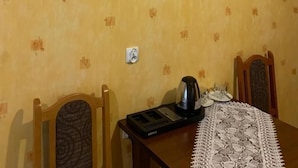 A dining area with a table set for two, a coffee maker, and a painting on the wall. - Hostel mPark Myslowice (Myslowice)