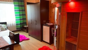 A compact room with a bed, a dining table, a small kitchen area, and a red pet. - Hostel mPark Myslowice (Myslowice)