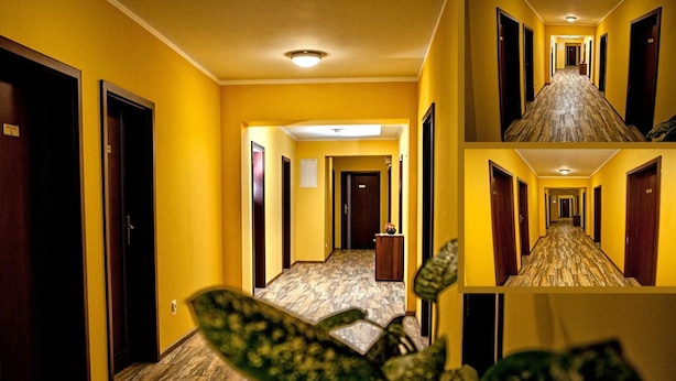 A hotel hallway with yellow walls, wooden doors, and a marble floor. - Hostel mPark Myslowice (Myslowice)