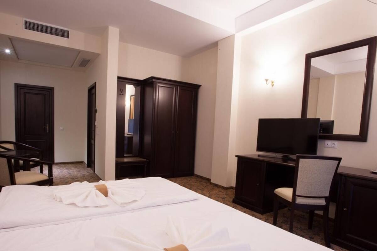 Une chambre d’hôtel équipée d’un lit, d’un bureau, d’une chaise, d’une télévision, d’une armoire et d’un miroir.