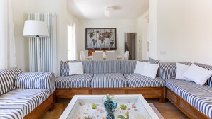 Ein Wohnzimmer mit einer gestreiften Sofagarnitur, einem Couchtisch mit Dekoration und einem Wandbild einer Weltkarte.