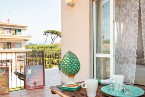 A balcony with a decorative lamp, a table with a white mug and glasses, and a poster. - Villa Franca (Pietrasanta)