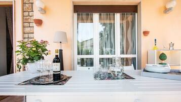 A dining table set with wine glasses, a bottle, and a pitcher, with a potted plant and decorative items on the table.