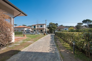 A residential street with houses, a stone pathway, and a hedge. - Villa Gloria (Pietrasanta)