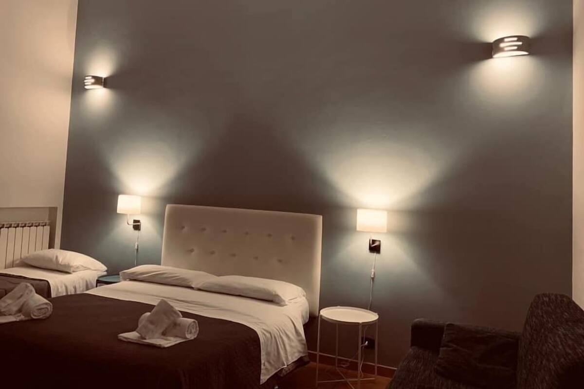 A hotel room with a large bed, two bedside tables, and two wall-mounted lamps.
