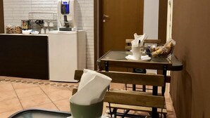 A hotel lobby with a reception desk, a coffee machine, a table with a napkin holder, and a door. - A Due Passi dal Ponte (Taranto)