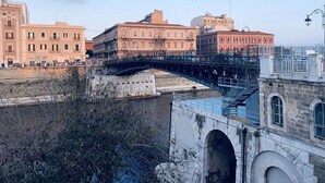 A bridge spanning a river with buildings on either side. - A Due Passi dal Ponte (Taranto)