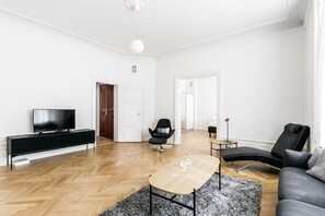 Ein modernes Wohnzimmer mit Flachbildfernseher, schwarzen und grauen Möbeln sowie Holzboden.