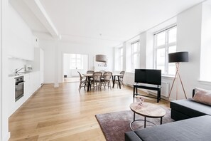 Ein großzügiger Wohnbereich mit Esstisch, Sofa und Fernseher.