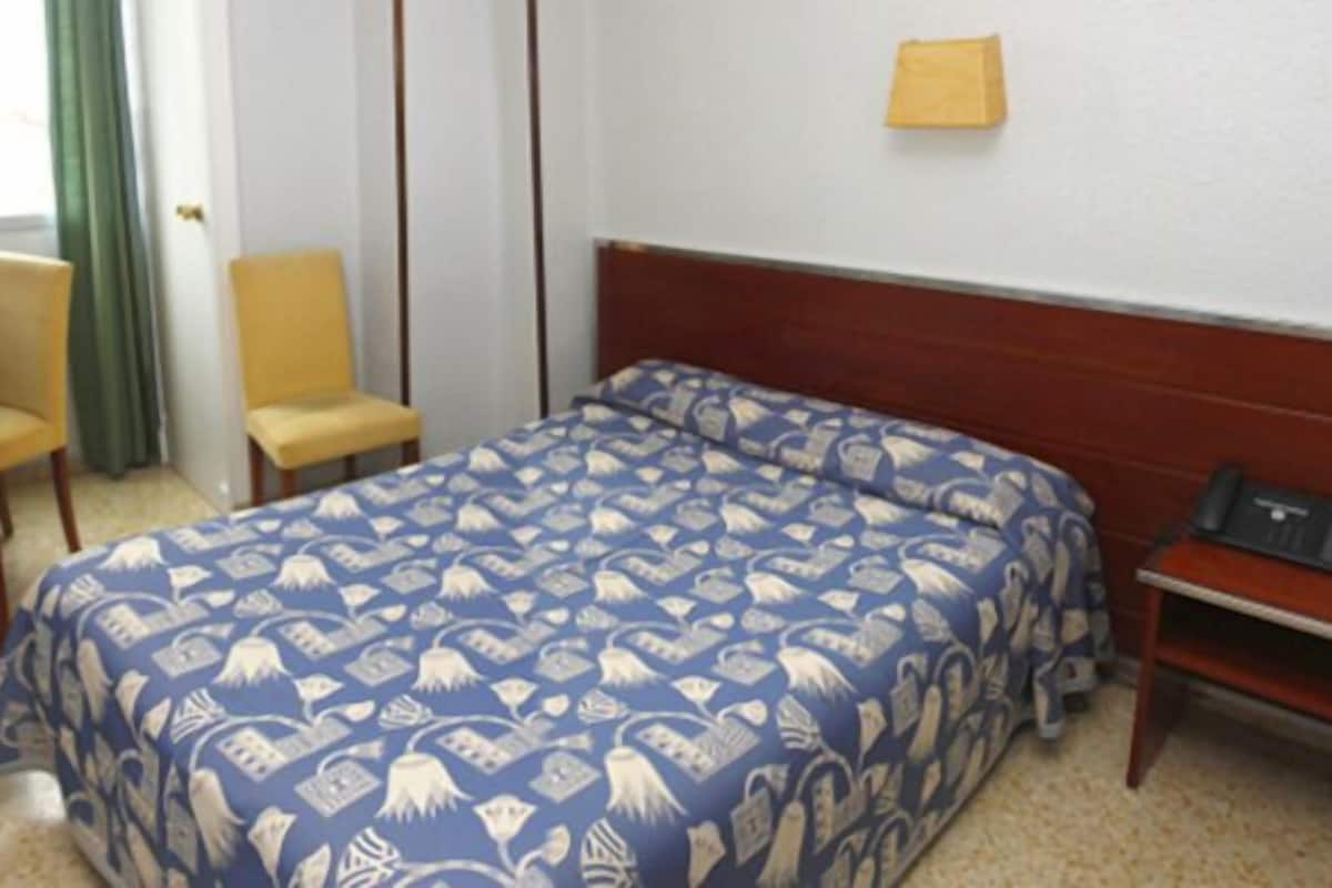 Ein Hotelzimmer mit Bett, Schreibtisch, Stuhl und Telefon.
