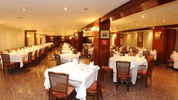 Un comedor de hotel con varias mesas dispuestas para comer, equipado con sillas y vajilla.
