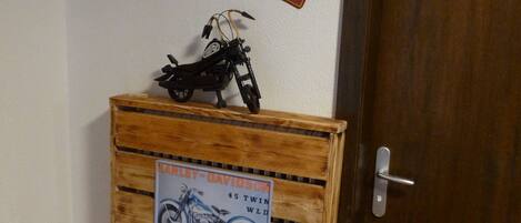 Een houten kast met een motorstickerset, een Florida nummerplaat en een deur met een bordje 'Gasten toilet'.