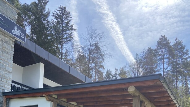 En moderne udendørs terrasse med et træpergola, stentrappetrin og en stenbænk.