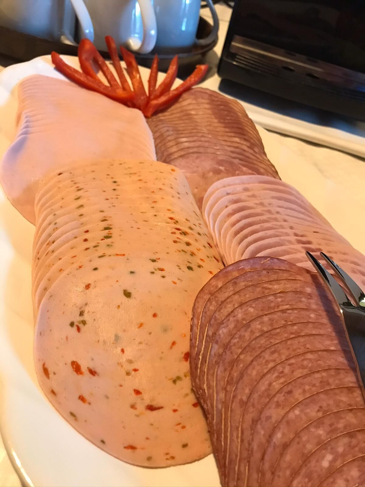 A plate with sliced meats and a large sausage.