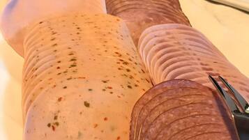 A plate with sliced meats and a large sausage.