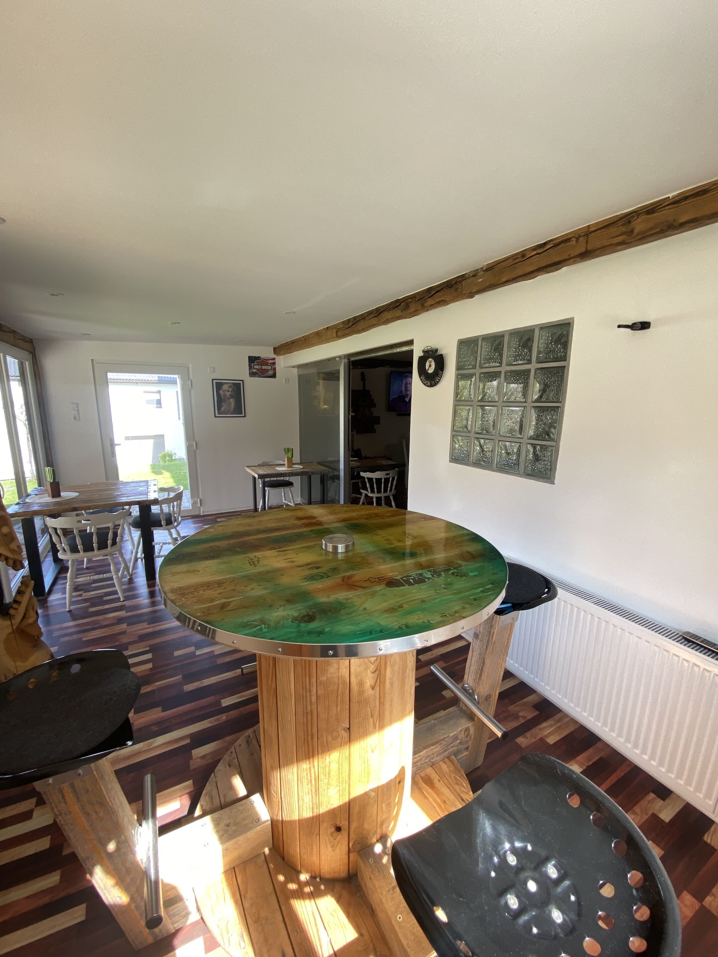 A dining area with a round wooden table, chairs, and a view of the outside.