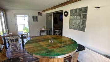 A dining area with a round wooden table, chairs, and a view of the outside.