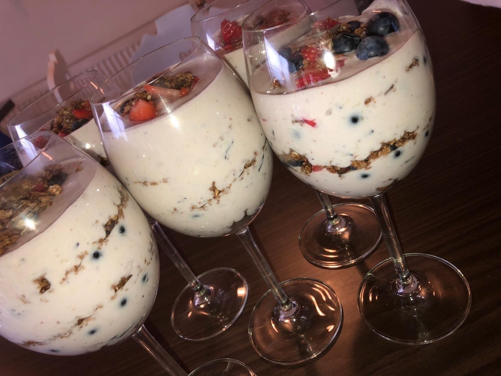 Tres vasos de postre en capas con frutas y granola.