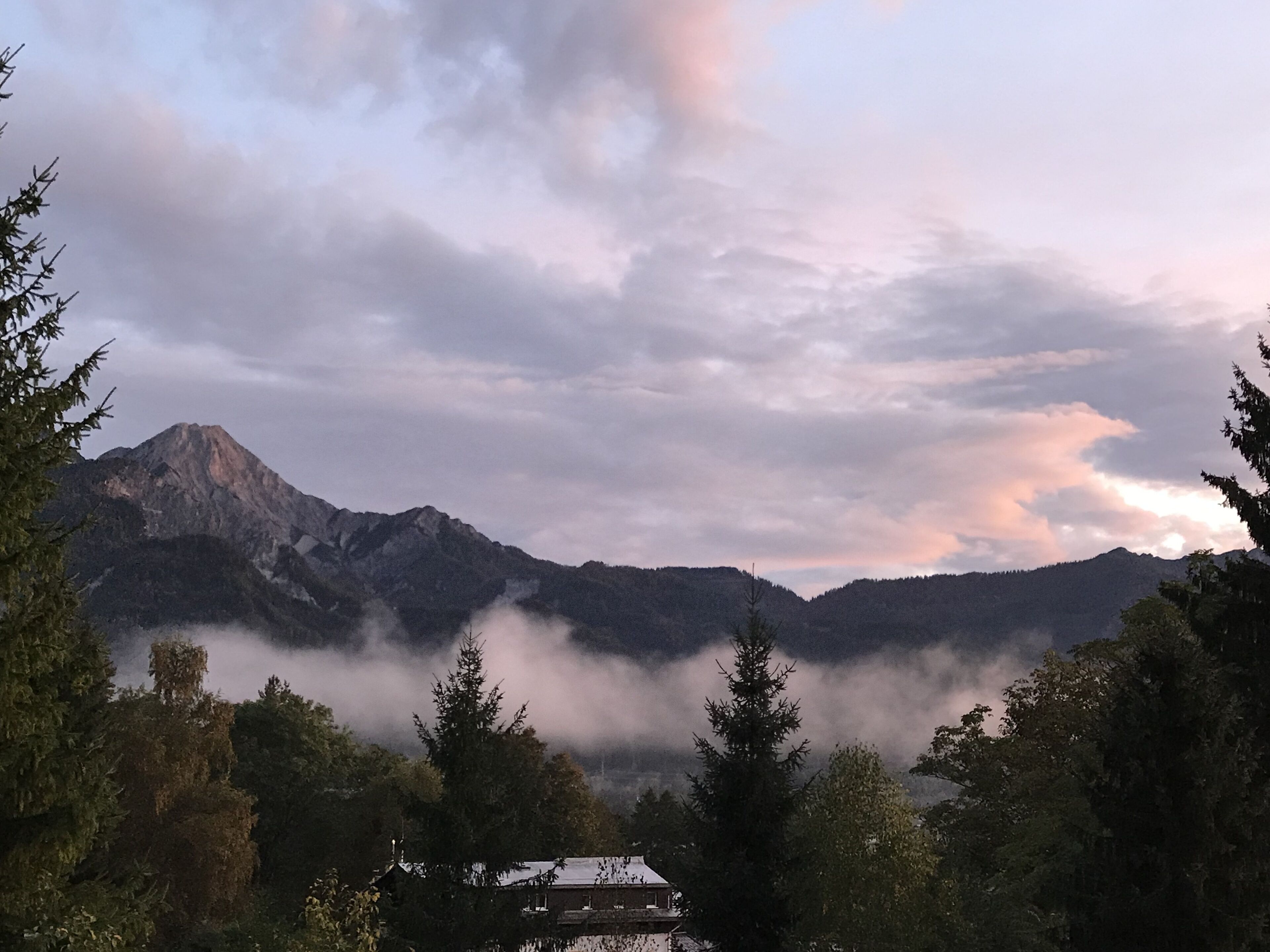 Un paisaje montañoso con una casa en primer plano.
