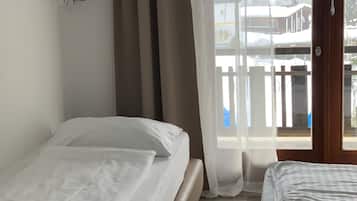 Une chambre d’hôtel avec deux lits, un téléviseur fixé au mur et un balcon donnant sur des immeubles.