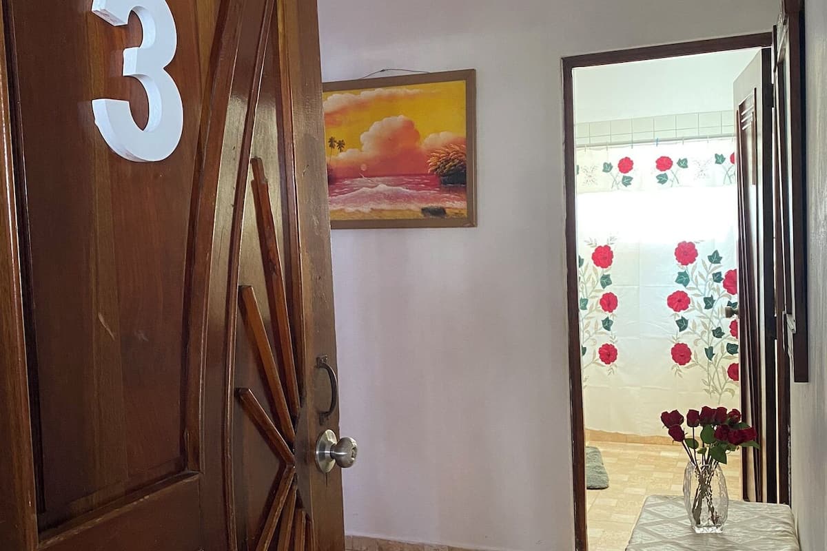 A wooden door with the number 3, a painting of a sunset, and a tiled floor.
