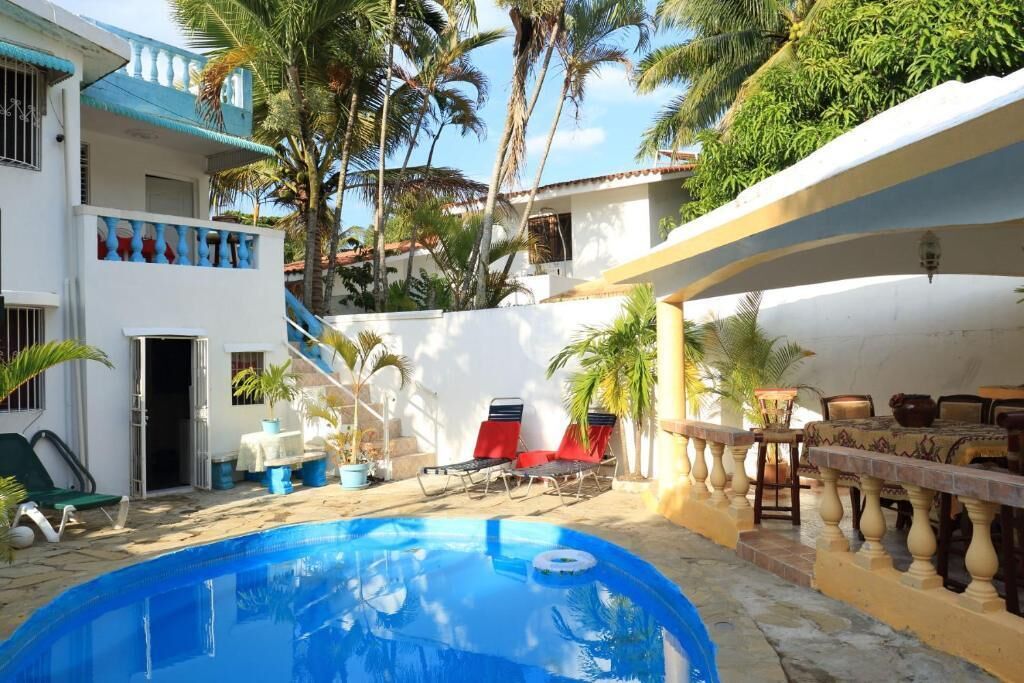 Un espace piscine avec des chaises longues, un bar et un escalier menant à un niveau supérieur.