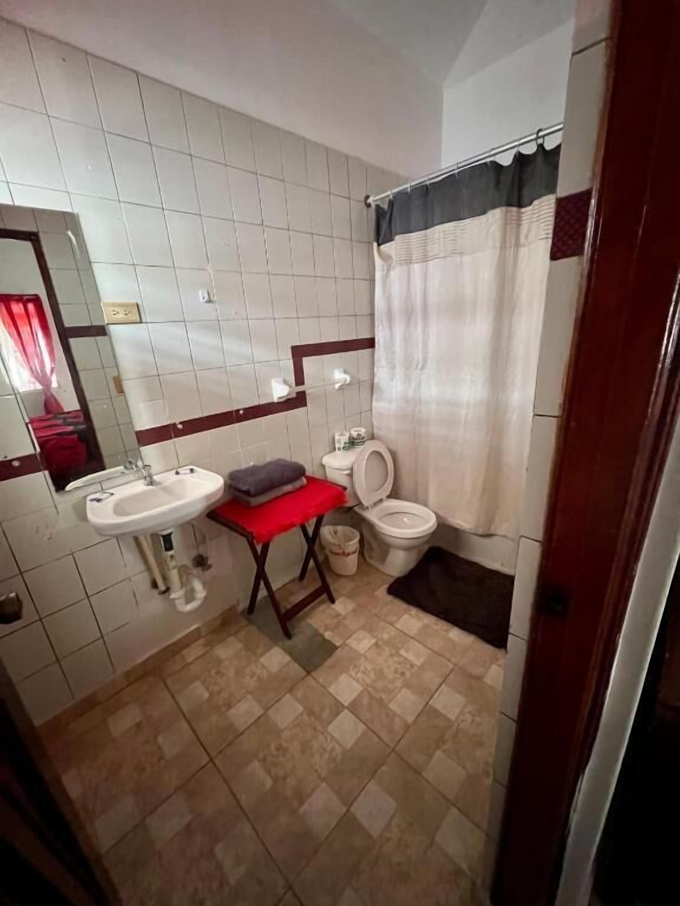 A small bathroom with a sink, toilet, and shower curtain.