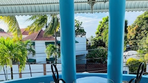 A covered outdoor seating area with two chairs and a table, surrounded by blue columns and a white ceiling. - Villa Antonia 16 (Sosúa)