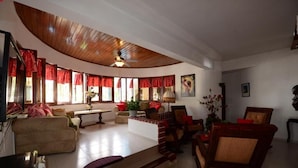 A spacious living room with a curved ceiling, large windows with red curtains, a sofa, a coffee table, and a fireplace. - Villa Antonia 16 (Sosúa)