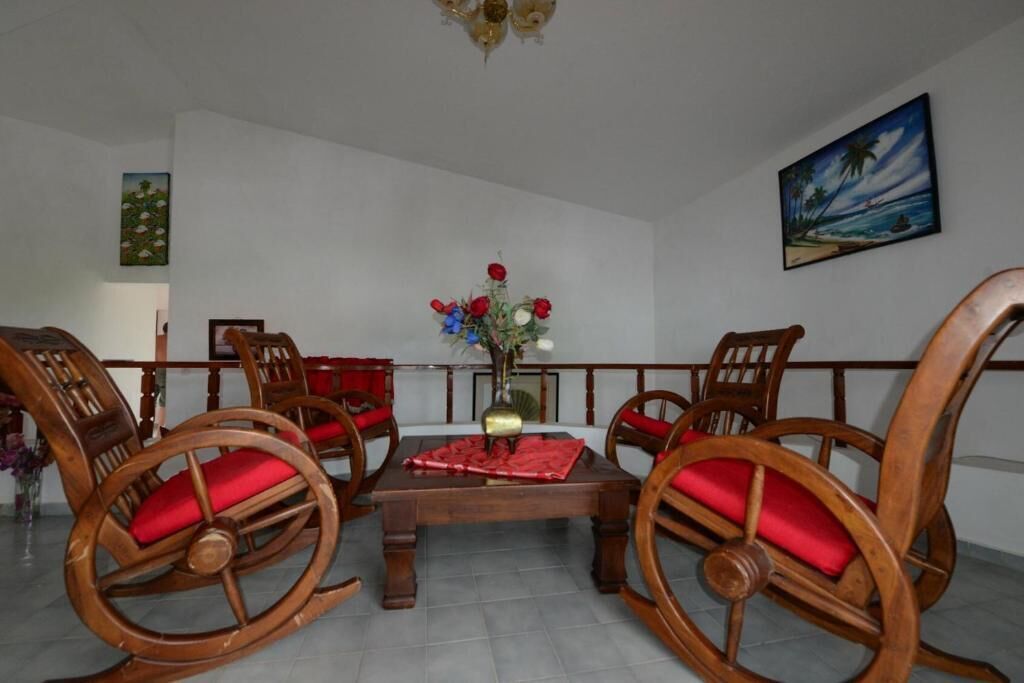 A dining area with a wooden table and chairs, a vase with flowers, and a painting on the wall.