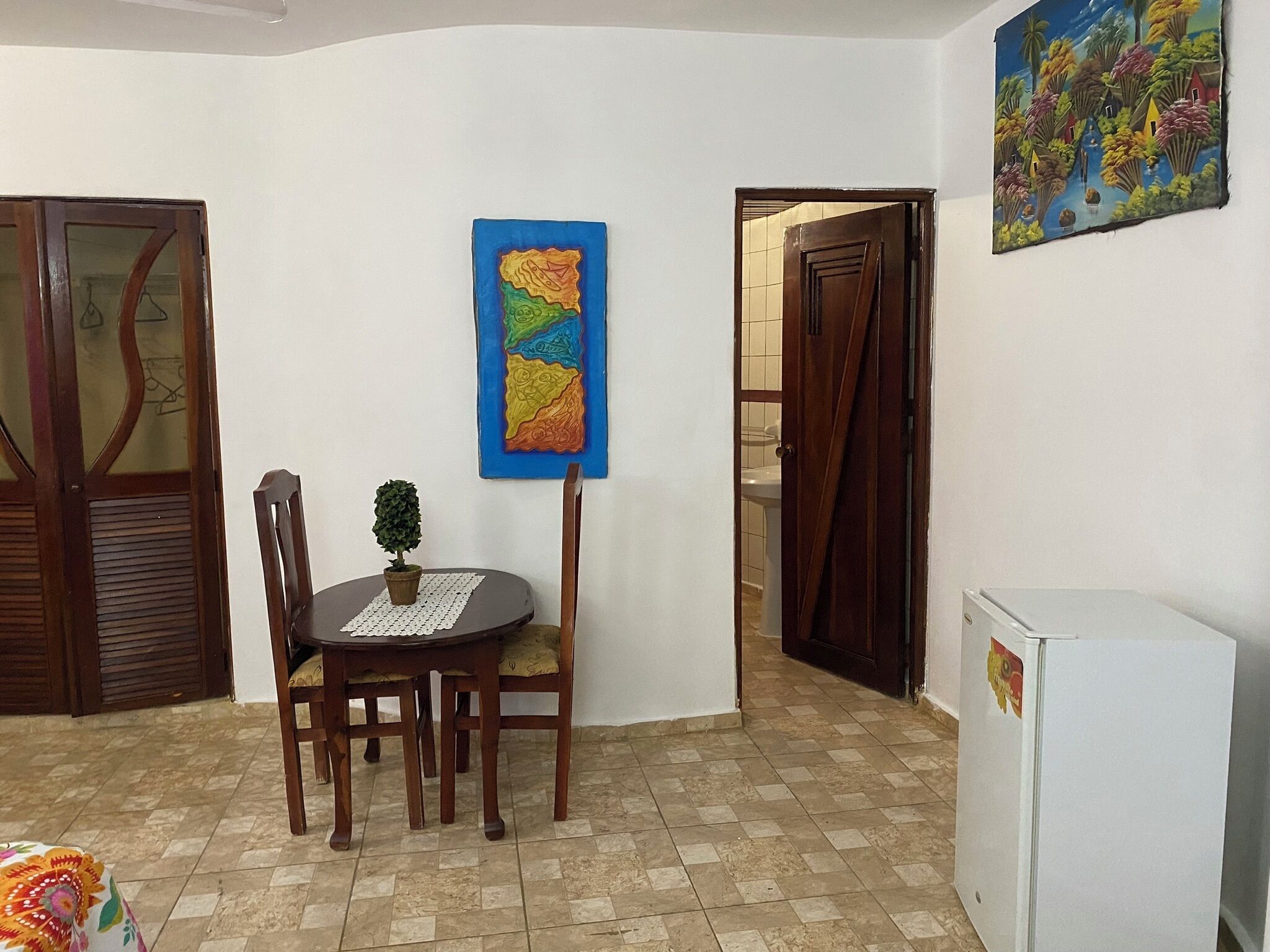 Un comedor con una mesa y sillas, una planta en maceta y un cuadro en la pared.