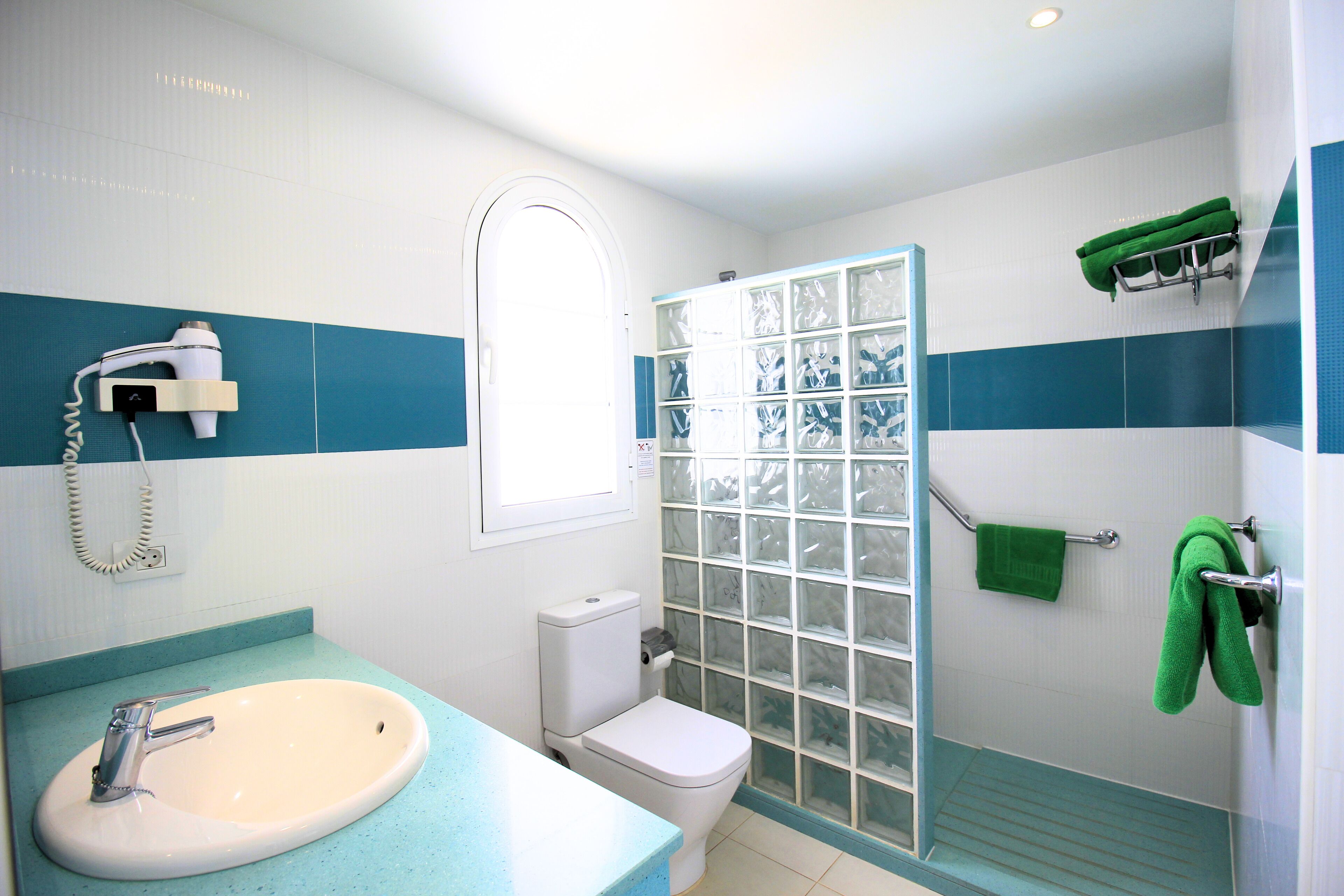 A bathroom with a white sink, a toilet, and a shower with a glass door.
