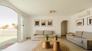 A modern living room with a sofa, two coffee tables, and a large glass door leading to a balcony.