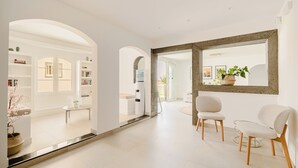 A modern interior with a hallway, seating area, and a large mirror.