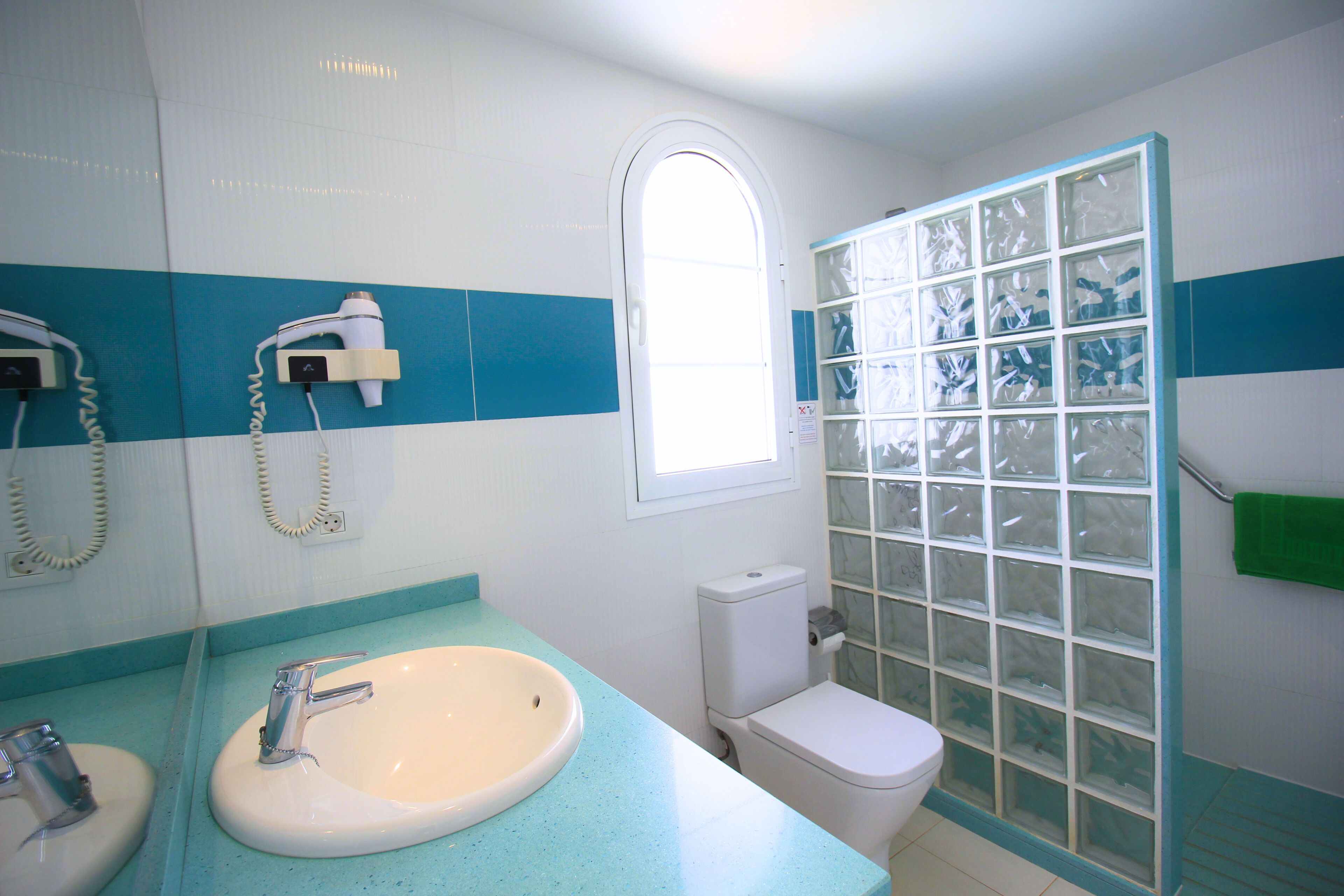 Une salle de bain avec un lavabo blanc, des toilettes et un espace douche doté d’une porte en verre.