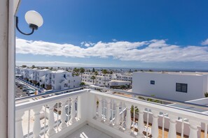 A balcony with white balustrades overlooking a coastal residential area with white buildings and a clear blue sky. - CORONA MAR APARTMENTS - SELECT ADULTS (+16)  (Tías)