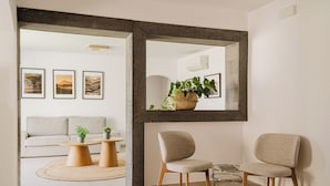 A modern living room with a sofa, two chairs, a coffee table, a mirror, and framed pictures on the wall.