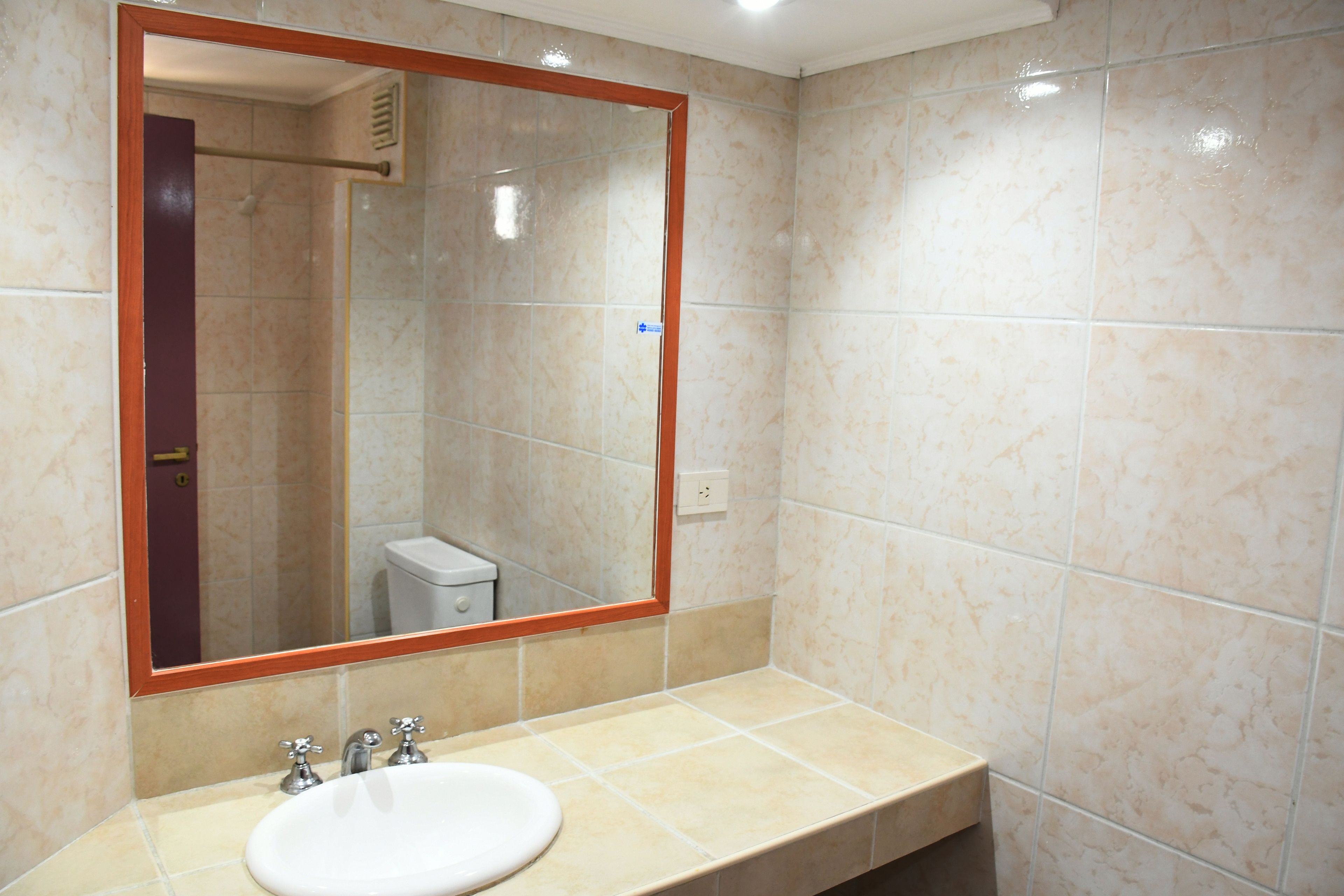 Un baño con un espejo grande, un lavabo y un inodoro.