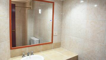 Un baño con un espejo grande, un lavabo y un inodoro.