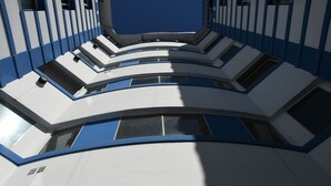 Ein modernes Gebäude mit gewölbter, mehrstöckiger Gestaltung, großen Fenstern und einem blau-weißen Farbdesign.