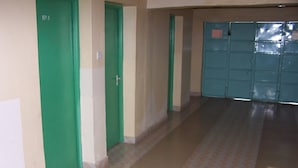 A corridor with green doors, a tiled floor, and a blue locker room. - Quest Resort (Nakuru)