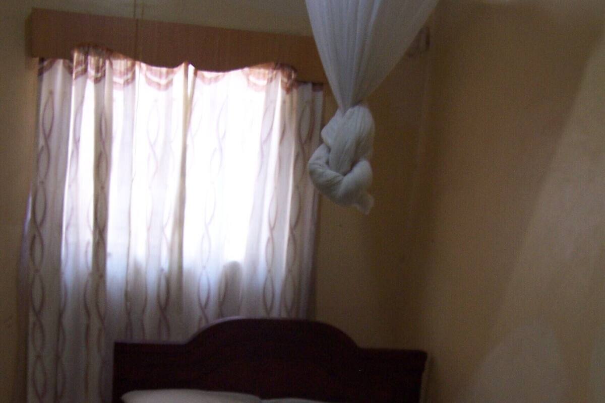 A single bed with a wooden headboard, white bedding, and a canopy.