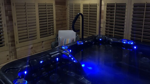 A room with a wooden interior, a hot tub with blue LED lights, and a towel rack. - Denver Blue Bear Romantic Spa Getaway: Private 1 BR Apartment with NEW Spa Room (Denver)