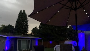 A patio area with a table and chairs, an umbrella, and string lights. - Denver Blue Bear Romantic Spa Getaway: Private 1 BR Apartment with NEW Spa Room (Denver)