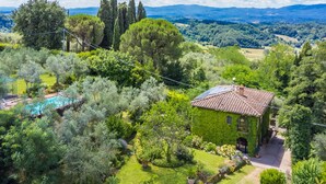 Uma vila cercada por vegetação exuberante, uma piscina e vista para montanhas distantes.