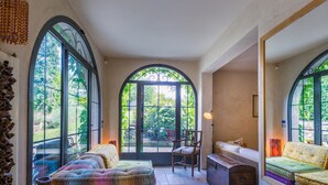 Um quarto aconchegante com uma janela grande, um sofá, um banco e um baú de madeira.