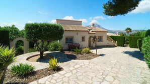 Una casa con tetto in tegole, un vialetto in pietra e una montagna sullo sfondo.